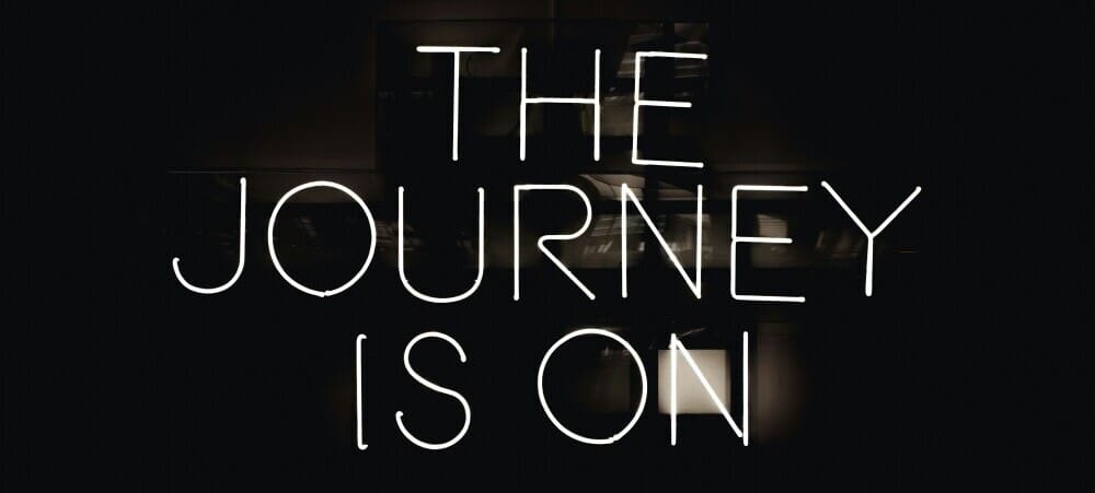Top Affiliate Marketing Jobs Neon on pitch black reads The Journey is On in this black and white image about getting started.